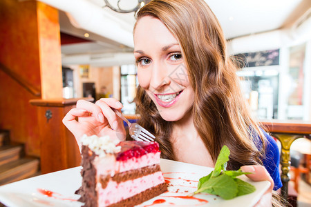 年轻妇女在咖啡馆吃蛋糕背景图片