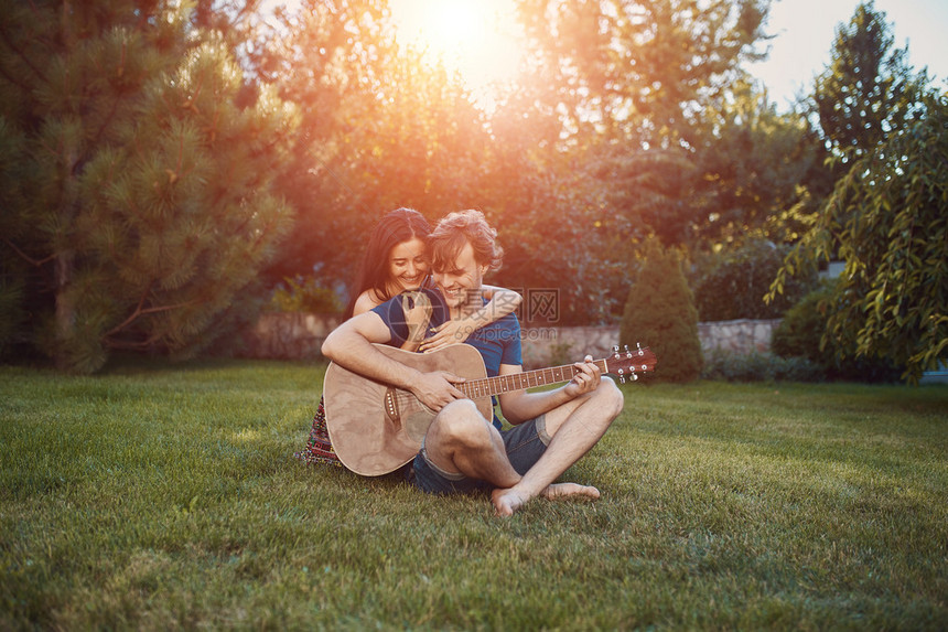 英俊的浪漫情侣坐在花园的草地上和男图片