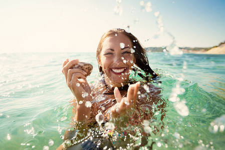 美丽的年轻女子在海边玩得开心图片