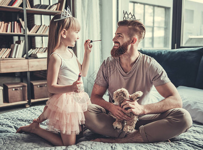 可爱的小女孩和她英俊的大胡子爸在她的房间里玩耍时微笑着女孩正在图片