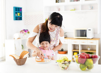 帮助母亲在厨房里做饭的小女孩图片