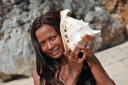年轻女子把海螺壳放在耳边背景图片