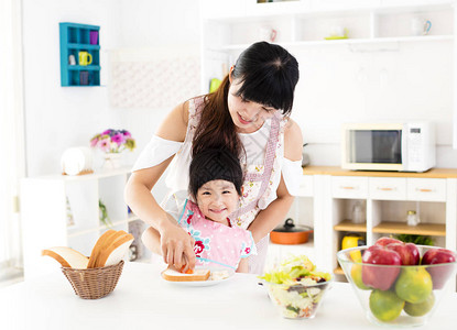 帮助母亲在厨房里做饭的小女孩图片