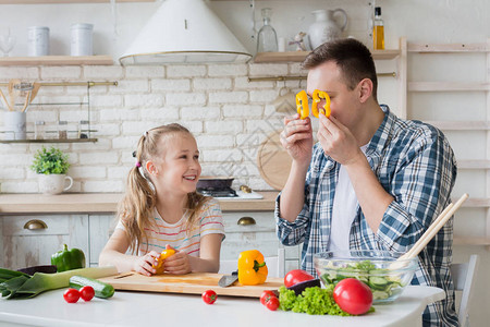父亲和女儿在一起做健康饭时玩胡椒图片
