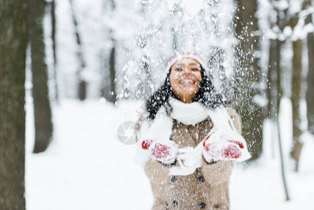 有魅力的非洲女人在公园里扔雪和在冬图片