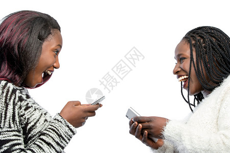 带着智能手机欢笑的非洲少女们的近距离肖像图片