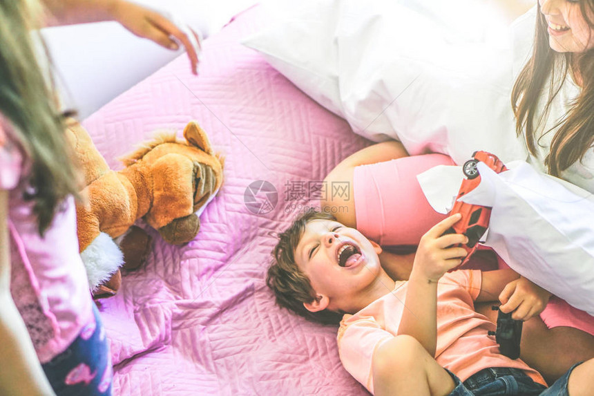 快乐的家庭孩子在床上玩具和枕头图片
