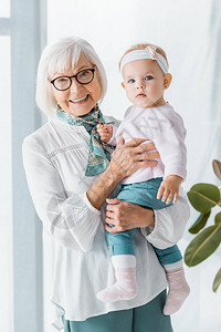 戴眼镜的快乐祖母抱着小孙女图片