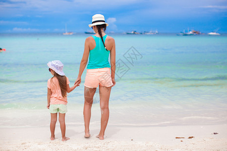 年轻美丽的母亲和可爱的小女儿在热带沙滩玩图片