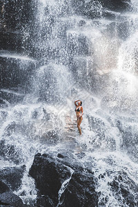 女人在大而美丽的瀑布流下享受图片