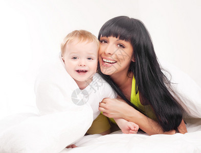 快乐的年轻母亲和在家床上的婴儿以图片