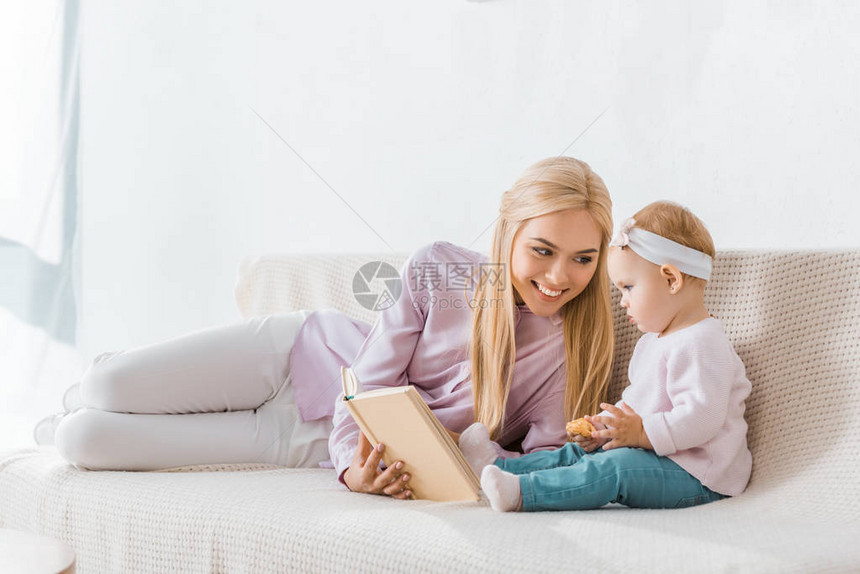 年轻笑的母亲读书给小女儿看书而图片