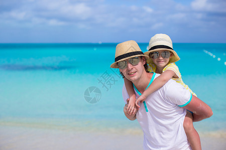 年轻父亲和他的可爱小女儿在热带海滩图片