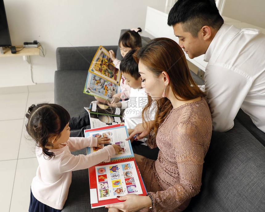 父母孩子家庭父亲母女儿子坐在沙发上阅读图片