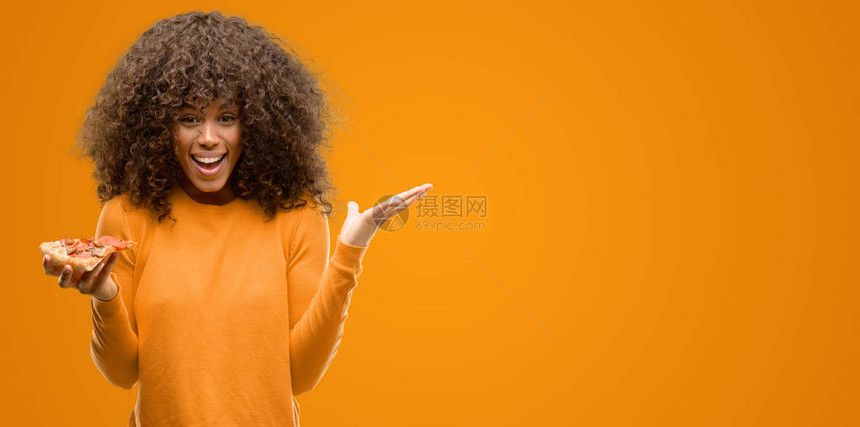 拿着披萨片的非洲裔美国女人非常高兴和奋图片