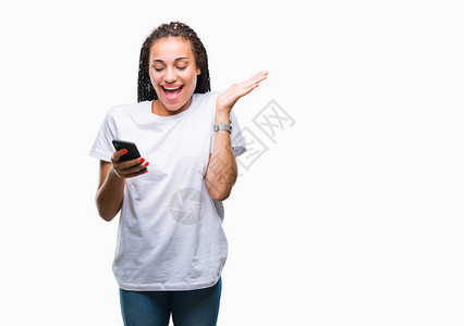 年轻的辫发非洲裔美国女孩在孤立的背景下使用智能手机表现得非常高兴和奋图片