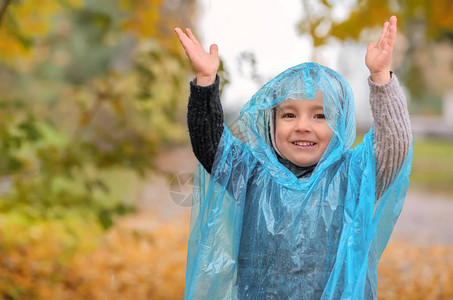穿雨衣的可爱小男孩在秋天图片
