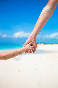 父亲和女儿在海滩手牵的特写图片