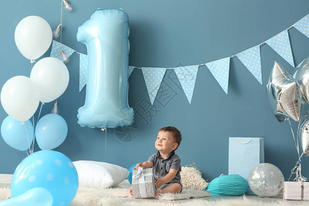 可爱的小男孩坐在毛地毯上房间装饰在生日派背景图片