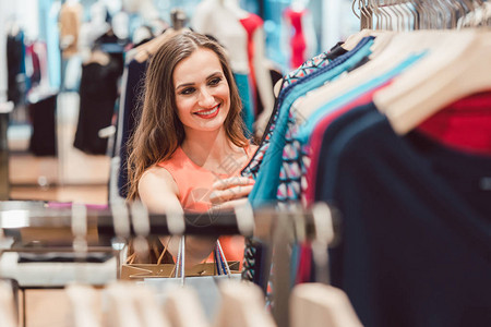 女人在时装店的衣架上浏览衣服图片