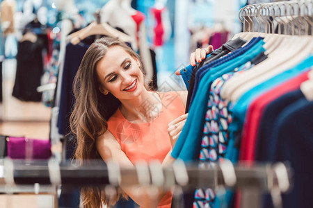 女人在时装店的衣架上浏览衣服图片