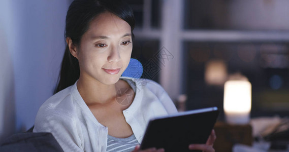 女人晚上在平板电脑上看图片