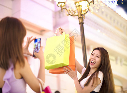 快乐的女子在商场对着购物袋拍照图片