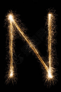 英文大字母N由黑色背景上的燃烧火花制成闪亮的节日派对烟花字体背景图片