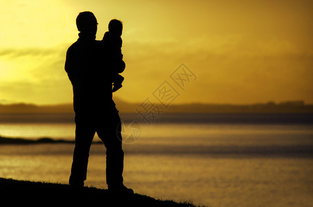 日落时一个年轻父亲的休眠在海图片