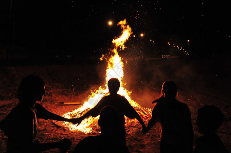 优西比奥儿童们手牵在营火周围背景