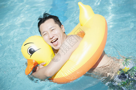 男人穿着黄色的鸭子充气管在游泳池里玩耍图片