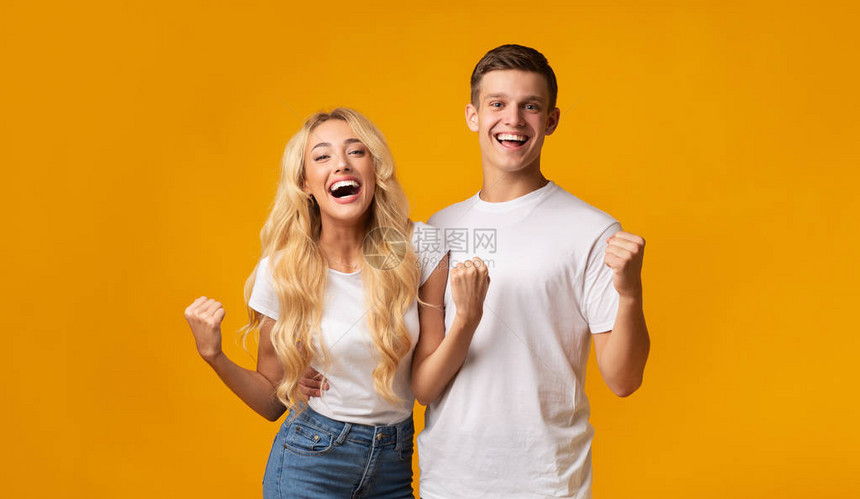 快乐的一对年轻夫妇以紧握的拳头庆祝成功图片