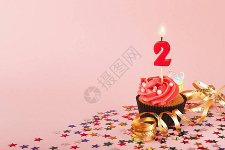 第二个生日蛋糕与蜡烛和粉红色背景上洒图片