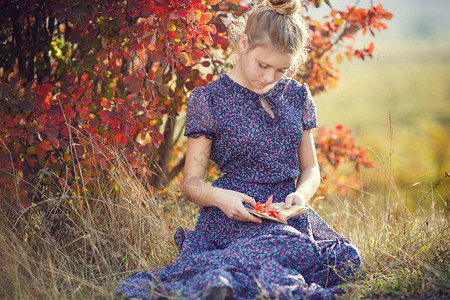 秋天公园里年轻漂亮的女孩看书图片
