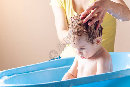 母亲洗头和在蓝色浴中毛发小男孩图片