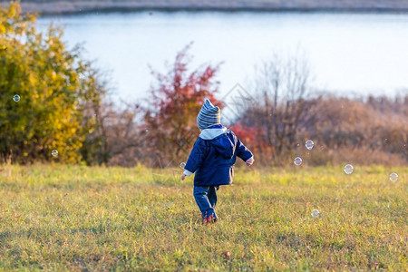 在秋天风景的户外野玩肥皂泡的小男孩图片