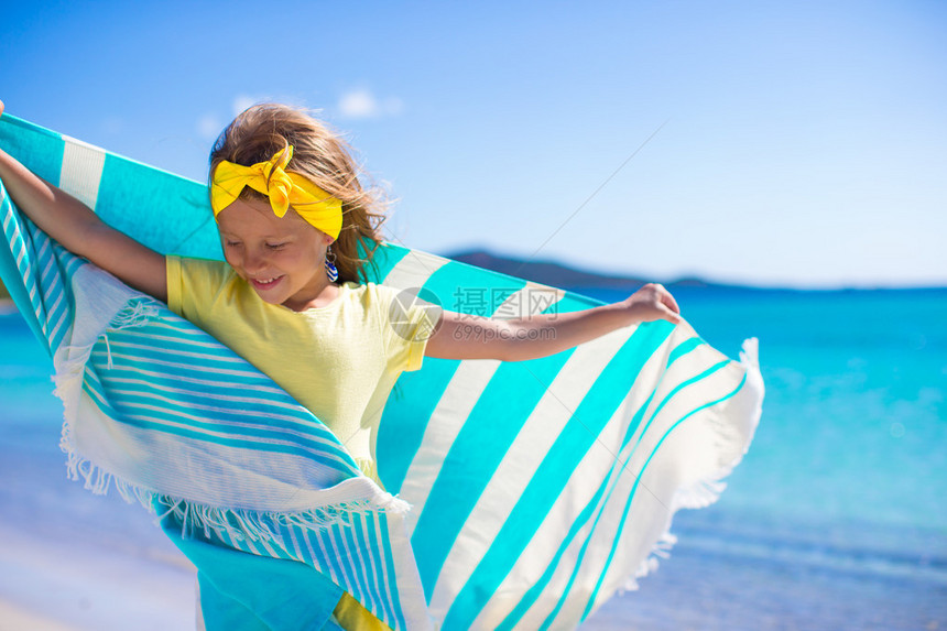 小女孩带着毛巾在沙滩上奔跑图片