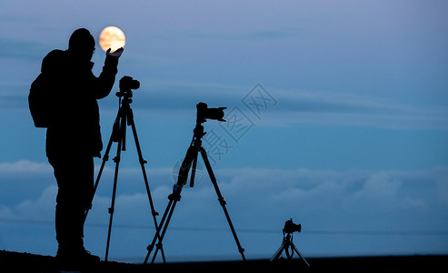 满月夜晚和Backlit摄影师带三脚架和摄像机的全月夜间和B背景图片