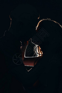 异恋情侣在黑暗中接吻的剪影背景图片