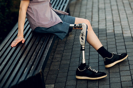 有假肢的残疾年轻人坐在户外图片