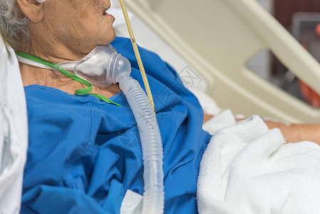 80多岁的老年病人在医院的床上使用呼吸器帮助呼吸背景图片