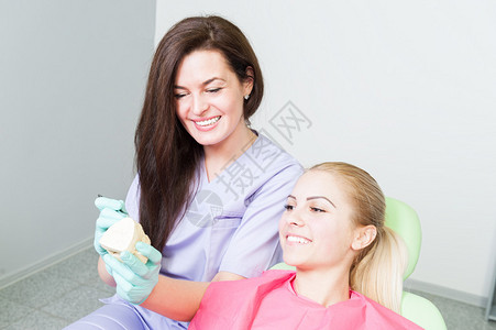 牙医妇女和患者将牙科植入物示例视图片