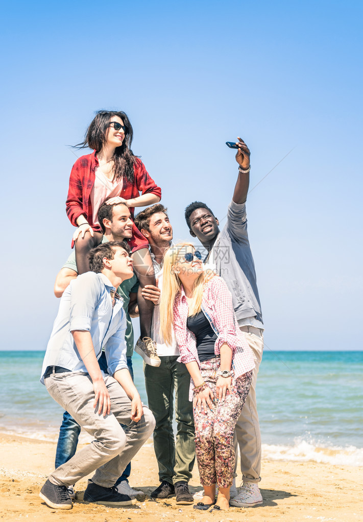 一群多种族快乐的朋友在海滩自拍图片