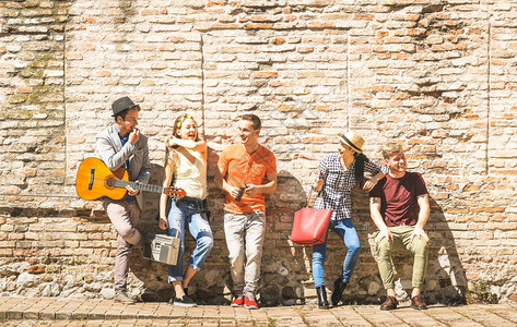 一群快乐兴奋的朋友在户外玩吉他欢呼年轻人在城市旅游中一起享受春夏时光温暖的午后滤色器上的背景图片