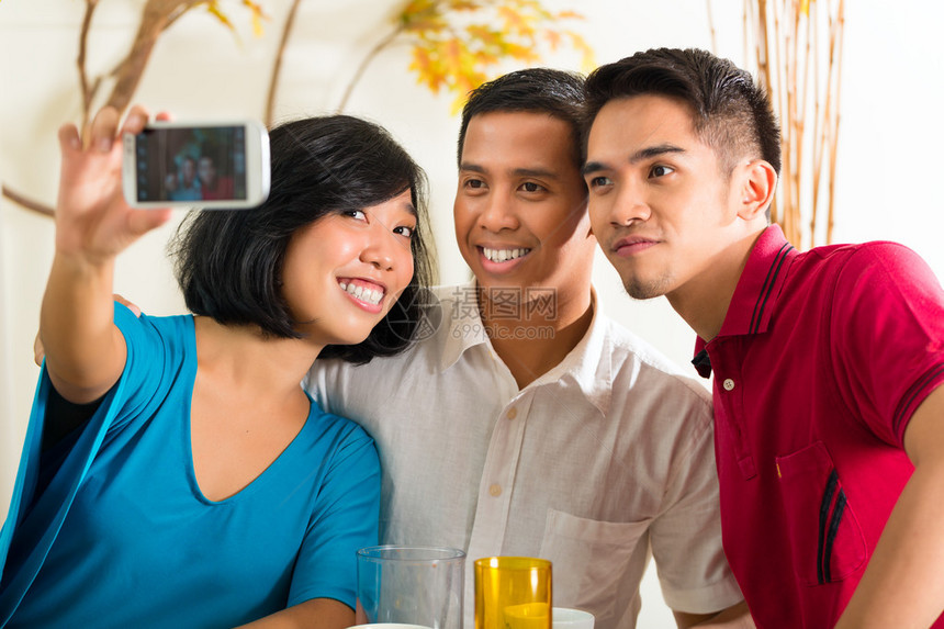 亚洲朋友两个男人和一个女人用手机拍图片