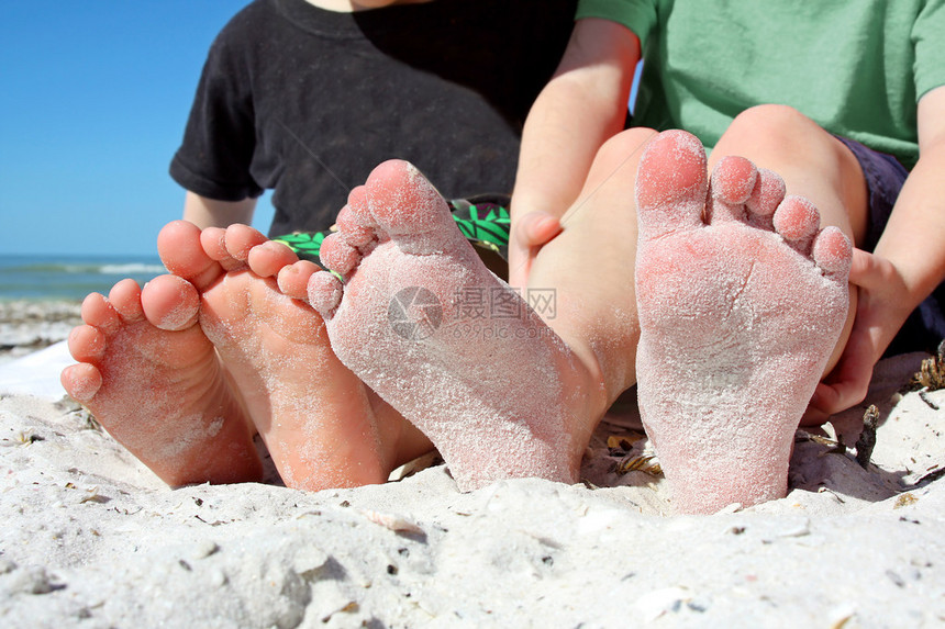 看见两个幼童的脚在海边滩上坐着图片