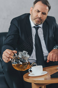 英俊的成熟商人把茶倒进杯子里背景图片