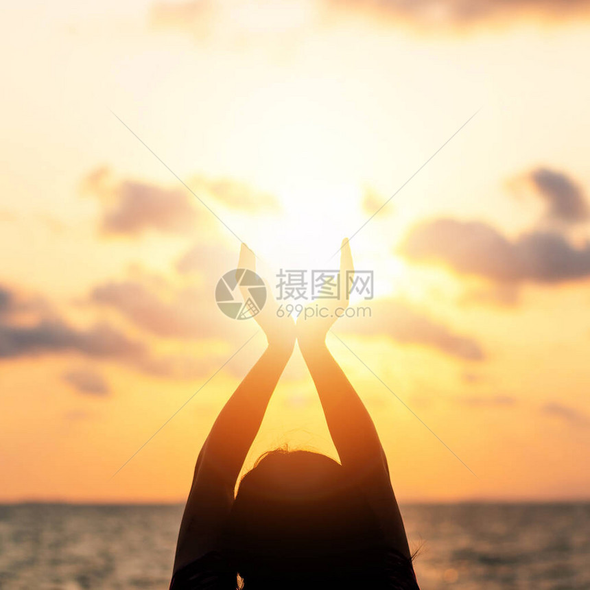 夏季太阳六月至日概念和快乐的年轻女子手的剪影在海滩上与海洋或大海背景的温暖的黄金时段天空中放松冥图片