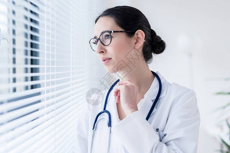 一名年轻女医生在现代医院或医疗中心休息时透过窗外看一眼时做白日图片