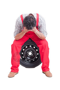 紧张的机械技工头靠手坐轮胎图片